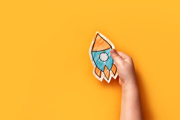The child holds a paper rocket in his hand. A symbol of early child development