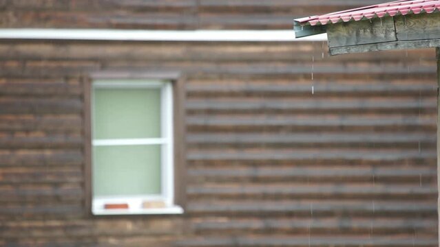 a downpour drains from the roof of a village house
