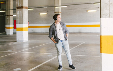 portrait of fashionable cool man on an industrial environment listening to music with earphones. High quality photo
