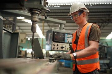 Portrait of Professional Heavy Industry Engineer / Worker Wearing Safety Uniform, Goggles and Hard Hat. In the Background Unfocused Large Industrial Factory