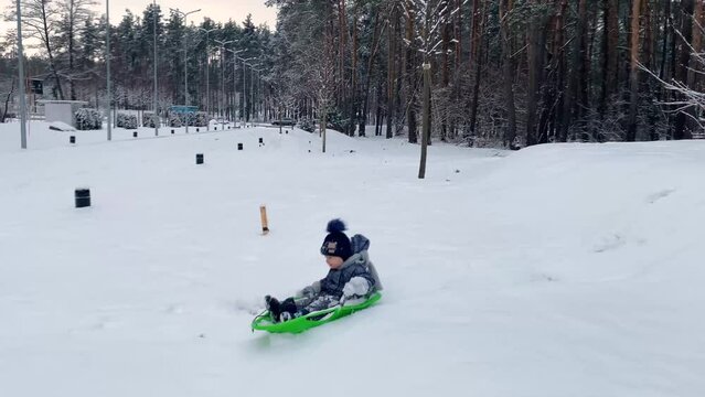 the father pushes the child down the slide on a sled