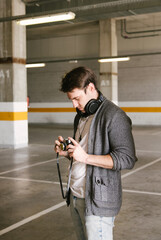 portrait of fashionable cool man on an industrial environment making a photo with a retro camera. vertical shot. High quality photo