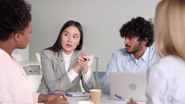 Young asian woman telling opinion speaking to multi-ethnic diverse colleagues