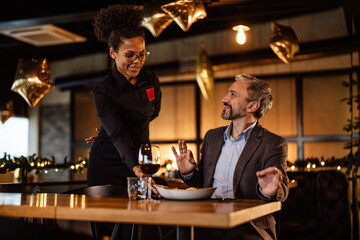 Hungry adult man, getting ready to have a tasty meal, brought by an african-american waitress.
