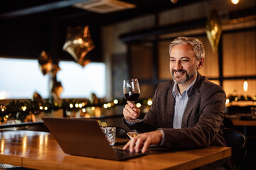 Satisfied caucasian man in a suit, browsing the internet while eating.
