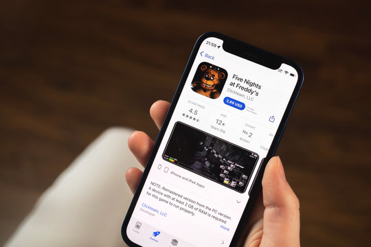 Five Nights at Freddy's FNAF game app. Girl holding mobile phone with game and want to play. Popular mobile games concept photo