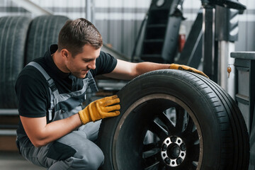Fototapeta na wymiar Replacement of the old tire. Man in uniform is working in the auto service