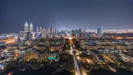 Fototapeta na wymiar Panorama of skyscrapers in Barsha Heights district and low rise buildings in Greens district aerial night timelapse.