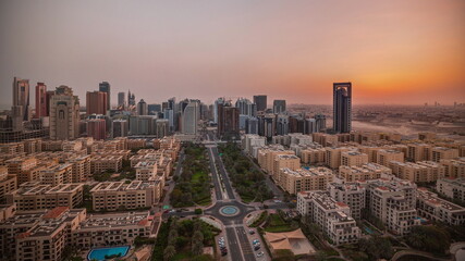 Fototapeta na wymiar Sunrise over skyscrapers in Barsha Heights district and low rise buildings in Greens district aerial timelapse.