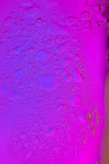 Oil and water drops on a glass in neon pink and purple gradient color. Close up shot. Vibrant bold colors and textures. Wallpaper abstract minimalist design. Copy space.