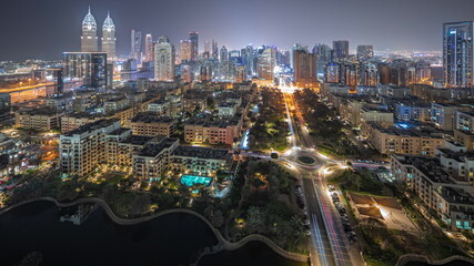 Panorama showing skyscrapers in Barsha Heights district and low rise buildings in Greens district aerial night timelapse.