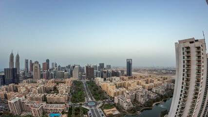 Fototapeta premium Panorama with skyscrapers in Barsha Heights district and low rise buildings in Greens district aerial day to night timelapse.