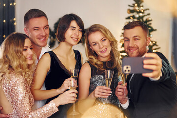 Making selfie. Group of people have a new year party indoors together