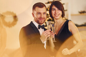 Illuminated by yellow light. Happy couple have a new year party indoors together