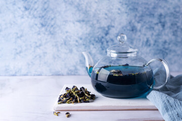 Herbal drink, glass teapot with blue tea with dry butterfly pea flower.