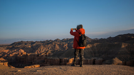 Woman hiker with backpack enjoying view. Travel through the canyon. Mountain gorge. Mountain landscape in autumn. Blue sky over canyon. Vintage tone filter effect with noise and grain.