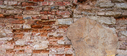 Fototapeta premium Abandoned grunge cracked brick stucco wall background. Old brick wall with peel stucco texture. Retro vintage worn wall wallpaper. Decayed cracked rough abstract banner surface.