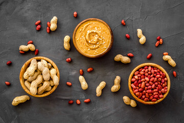 Creamy peanut butter and nuts in wooden bowls, top view
