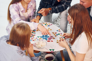 Playing puzzle game. Group of friends have party indoors together