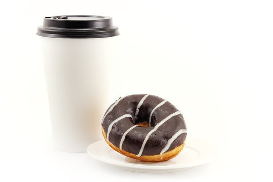 Chocolate doughnut on plate and blank disposable takeaway paper coffee cup isolated on a white background with copy space. Concept background of serving takeaway food for a coffee shop or bakery