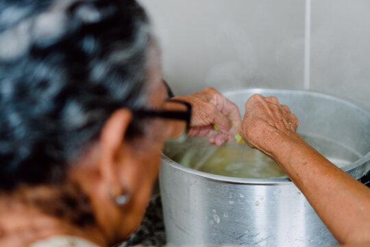 Unrecognizable Older Woman Making Lunch In The Kitchen And Stirring Soup.