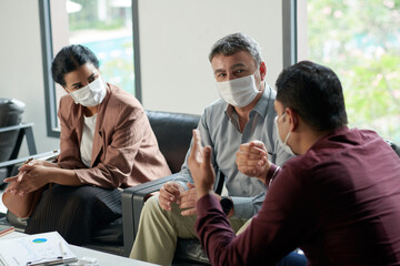 Fototapeta premium Business team in medical masks discussing important issues at meeting in office
