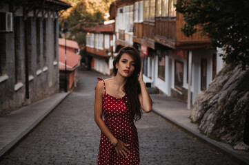 Sexy young Caucasian girl in a red dress posing on a beautiful historical street in Europe