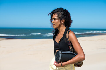 Woman walking with bluetooth speaker along coast