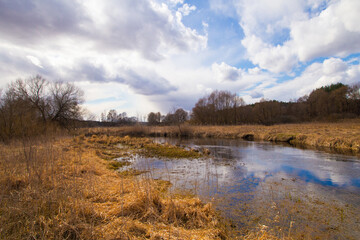 Spring in Belarus. Dry yellow grass, blue sky reflecting in the river. Warm pleasant april sunny day country side photo