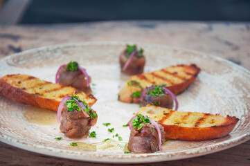 Grilled bread slices with olive oil, herbs and roll anchovies. Spanish bar food anchovy tapas