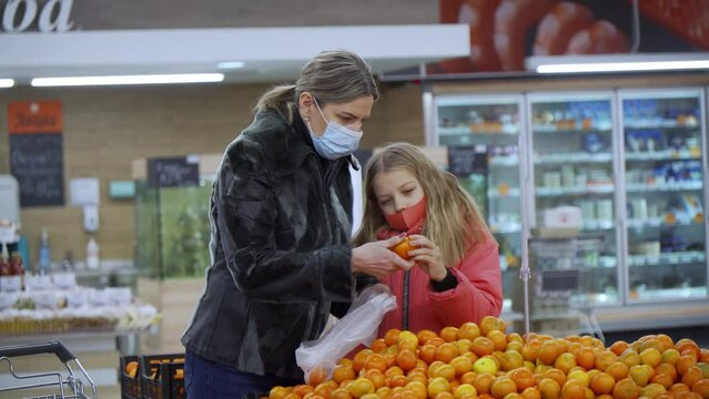 Mother and daughter choose the products in the store. They bundle the oranges they want to buy.