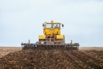 Soil tillage with a tractor. Pulls disc harrow in back view.