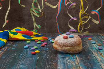 Doughnut with colorful decoration on a wooden table with streamer and a bow tie in the background