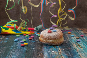 Doughnut with colorful decoration on a wooden table with streamer and a bow tie in the background