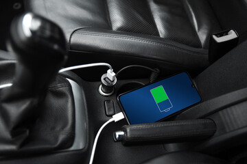 Mobile phone ,smartphone, cellphone is charged ,charge battery with usb charger in the inside of car. modern black car interior