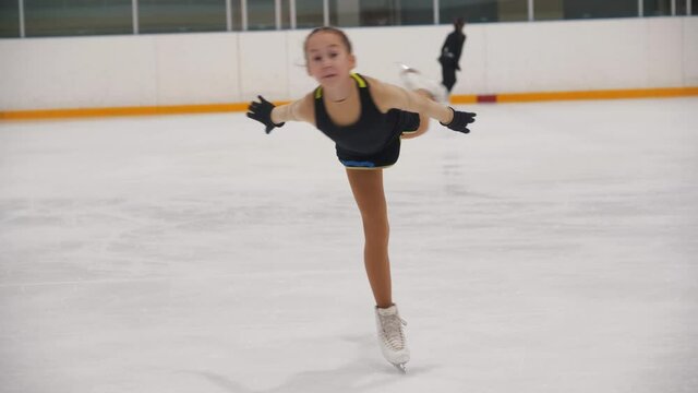 A little girl training her figure ice skating on the public rink - performing spinning on the spot