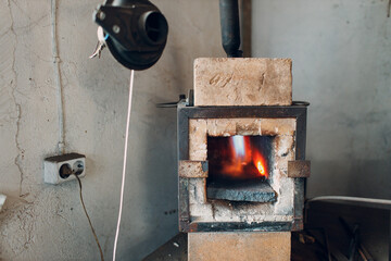 Blacksmith forge oven with hot flame. Smith heating iron piece of steel in fire of red-hot forge.