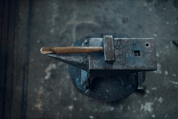 Blacksmith's hammer on metal anvil at forge. Overhead view