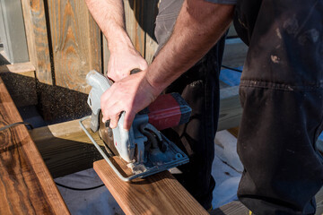handyman hand cutting wood with circular saw
