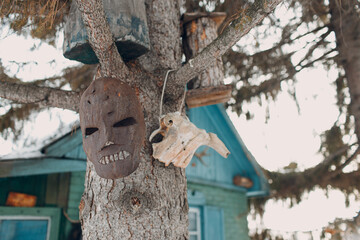 Old rusted scary metal maniac mask hanging on tree