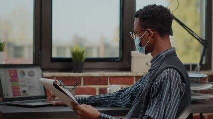 Business man with face mask analyzing commercial data on laptop and papers. Office worker planning financial project and investment with sales statistics. Accountant career job - Powered by Adobe