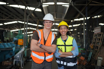 Portrait of male and female engineers working in the metalwork industry. Technical working with lathe machine at factory facility