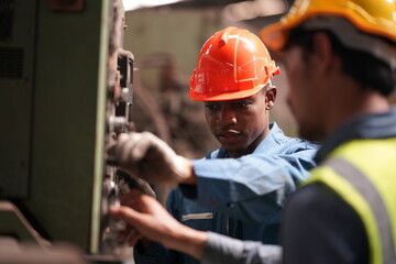 Portrait of Professional Heavy Industry Engineer / Worker Wearing Safety Uniform, Goggles and Hard Hat. In the Background Unfocused Large Industrial Factory