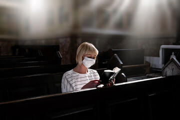 Masked woman is praying in the church. Religious concept, light of spiritual state. Close-up girl...