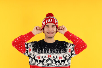 Attractive guy in Christmas sweater on yellow background