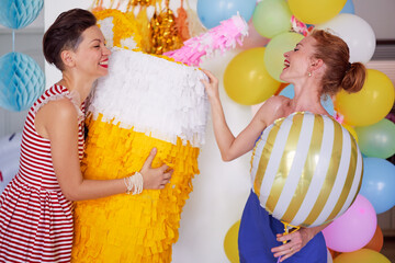 Party and celebration. Two happy smiling young women having fun together at home decorated with air baloons.