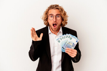 Young caucasian business man holding banknotes isolated on white background surprised and shocked.