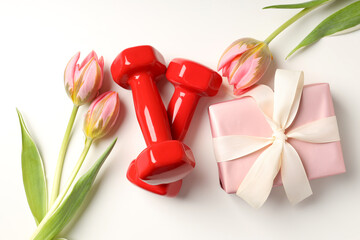 Gift box, tulips and dumbbells on white background