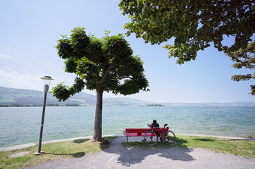 Man siiting on bench enjoying wonderful view of lake.