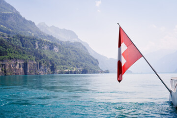 Fototapeta premium National flag of Switzerland with beautiful mountains and lake view.